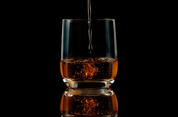 Brandy is poured into a glass on a black background