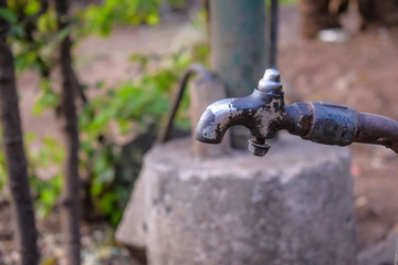 front view of old rusty red color faucet with white color pipe installed on yellow color painted wall. Picture captured at Kolhapur, Maharshtra, India. focus on object.