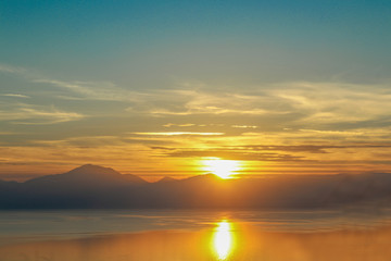 Fototapeta na wymiar Dramatic sunset reflected in the water over the gulf of Corinth on mainland Greece headed up the mountains toward Delphi from the west