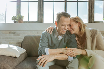 Pleasant good-looking middle-age couple hugging each other and smiling
