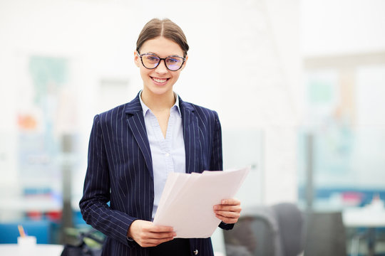 Waist up portrait of smiling young businesswoman wearing glasses smiling at camera, copy space