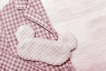 Red checkered warm Pajamas for Womens and eye mask for sleeping on wooden surface. Top view. Flat lay.