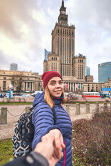 Obraz premium Young female tourist near the Palace of Culture and Science in Warsaw, follow me concept. Having a happy vacation in Poland