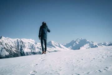 Fototapeta na wymiar Mann im Schnee in den Bergen, Aussicht auf die Berge, blau, weiße Berge