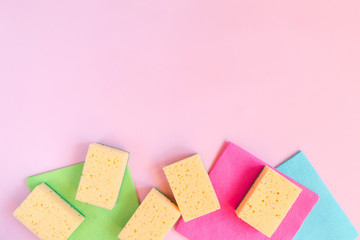 Cleaning concept A set of cleaning tools, rags, sponges, brushes, hands in rubber gloves on a light pink background, top view, flat lay, close-up
