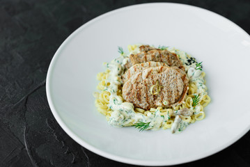 Dish with meat pieces, pasta, greens, sauce from a foie gras and the olive earth