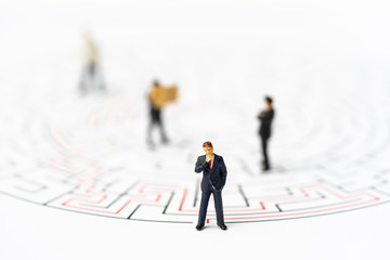 Miniature people, businessman in the labyrinth or maze figuring out the way out. Business concept, finding solution, strategic, and business opportunity.