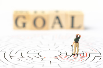 Miniature people, golf player in the labyrinth or maze figuring out the way out with word text "GOAL". Business concept, finding solution, strategic, and business opportunity.