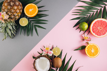 Summer fruits. Tropical palm leaves, pineapple, coconut, grapefruit, orange and lime on pink background. Flat lay, top view, copy space