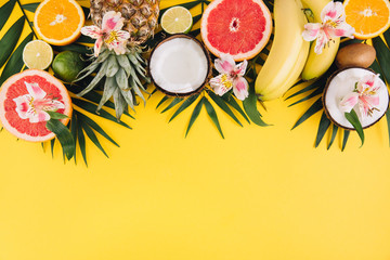 Summer fruits. Tropical palm leaves, pineapple, coconut, grapefruit, orange and bananas on pink background. Flat lay, top view, copy space
