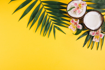 Summer fruits. Tropical palm leaves and coconut on yellow background. Flat lay, top view, copy space