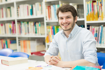 Handsome young male student doing homework at the library