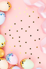 Festive Happy Easter background with decorated eggs, flowers, candy and ribbons in pastel colors on pink. Copy space