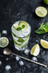 Mojito cocktail with lime and mint in highball glass on a dark stone background. Fresh summer cocktail