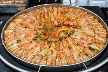 Close up of a freshly cooked large pan of sarmale, traditional Romanian cabbage rolls, with hot pepper and dill in display at a food market