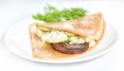 Thin delicious pancake with meat steak and mashed potatoes on white