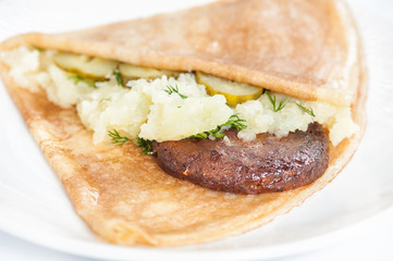 Thin delicious pancake with meat steak and mashed potatoes on white