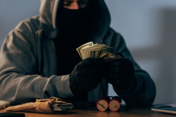 Partial view of terrorist in mask counting dollar banknotes