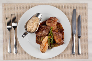 Fried meat in an assortment on a white plate with sauce.