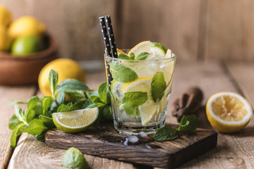 Mojito cocktail with lime, lemon and mint in a glass on a dark rustic background. Fresh summer...