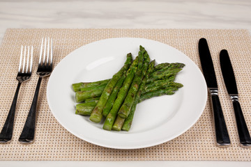 Green asparagus beans on a white round plate.