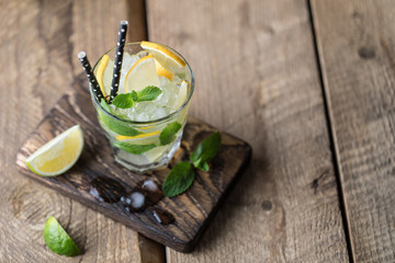 Mojito cocktail with lime, lemon and mint in a glass on a dark rustic background. Fresh summer cocktail. Lemon mojito