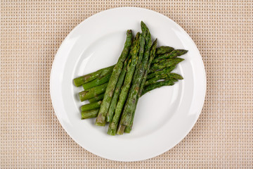 Green asparagus beans on a white round plate.