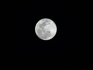 Beautiful bright full Moon in the night sky, lighting up all the colours below it