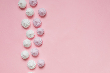 white and pink twisted meringues in a shape of pyramid on pink background, greeting card, copy space