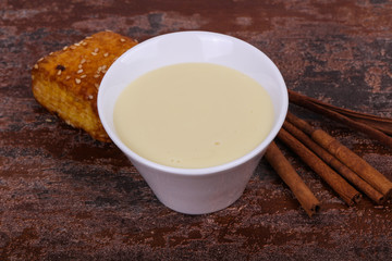 Condenced milk in the bowl with sinnamon and pastry