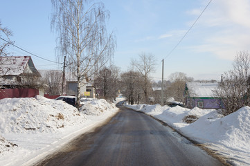 Wet asphalt road with snow drifts on the sides