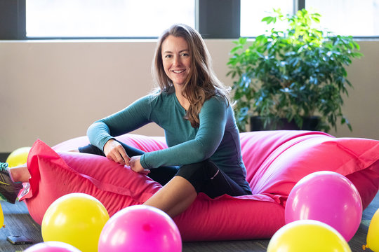 Redhead Woman Sitting On Pink Bean Bag Chair