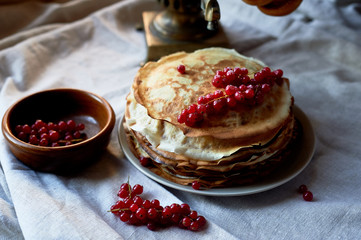 A stack of pancakes with red juicy currants.