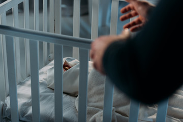Cropped view of criminal kidnapping newborn child from crib