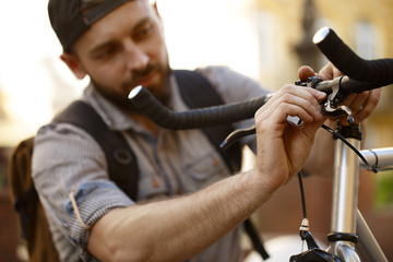 Young man repairing his bicycle on the street