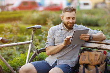 Handsome bearded male tourist using digital tablet at the city