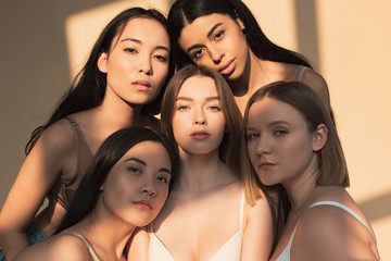 five beautiful multicultural young women looking at camera in sunlight