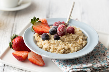 Breakfast oatmeal porridge with fruits berries and coffee cup. Oatmeal with strawberries and banana. Healthy breakfast concept.