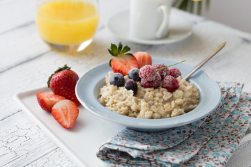 Breakfast oatmeal porridge with fruits berries and coffee cup. Oatmeal with strawberries and banana. Healthy breakfast concept.