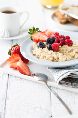 Breakfast oatmeal porridge with fruits berries and coffee cup. Oatmeal with strawberries and banana. Healthy breakfast concept.