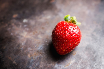 Fresh ripe strawberry on the dark rustic background. Selective focus. Shallow depth of field.