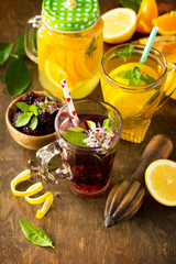 Refreshing summer berry Lemonade, lemon mint Tea and orange Lemonade with rosemary on wooden table in rustic style. Copy space.