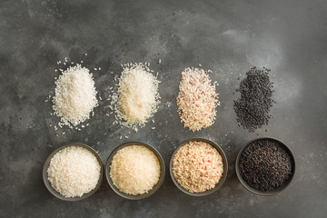 Different varieties of rice. Black rice in bowl on black. Top view.