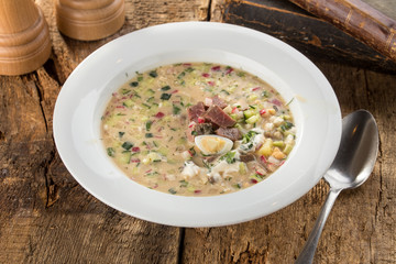 Summer cold soup okroshka with radish, cucumber and beef on wooden board
