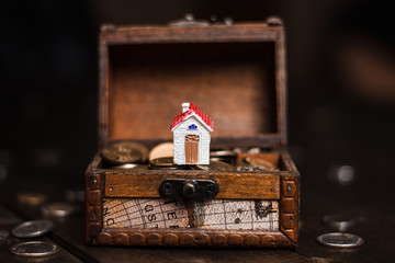 Miniature model house on treasure chest with coins. Concept of Investment management