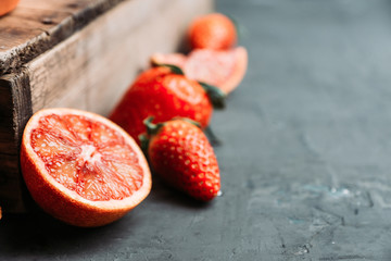Fresh ripe strawberry and red oranges on the dark rustic background. Selective focus. Shallow depth of field. 