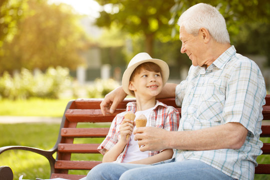 Little boy and his grandfather eating ice cream together at the park