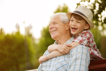 Happy boy and his grandpa enjoying warm day outdoors