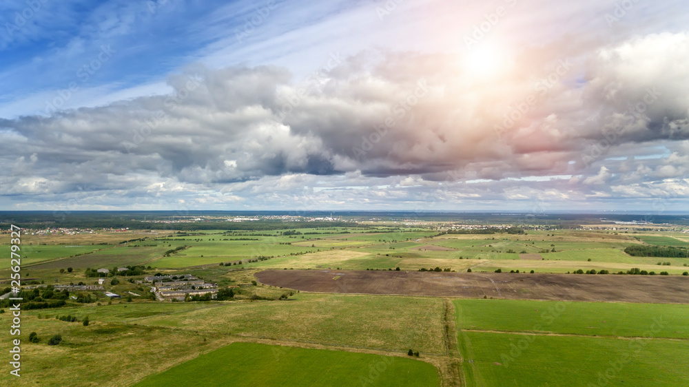 Wall mural drone view on the field with a green grass and the village in the distance...