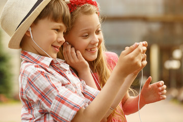 Little boy and girl using smart phone together outdoors